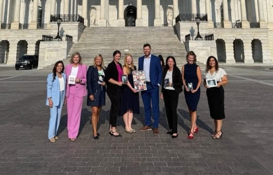 A group of people standing in front of the U.S. Capitol, holding framed photos of babies