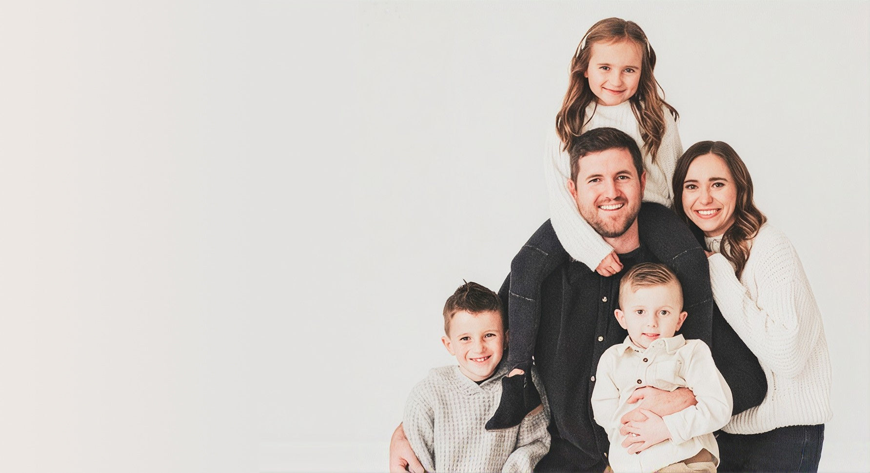 A smiling family of five posed together in a studio